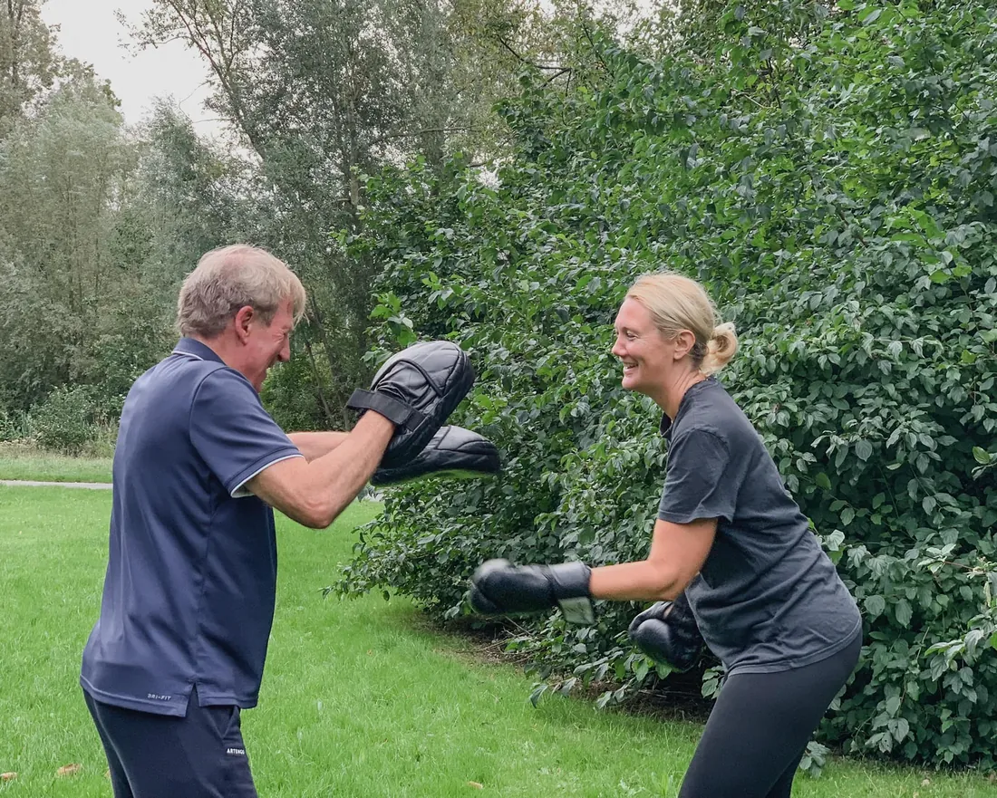Lid bokst lachend met de trainer tijdens een buitentraining bij Club Vit