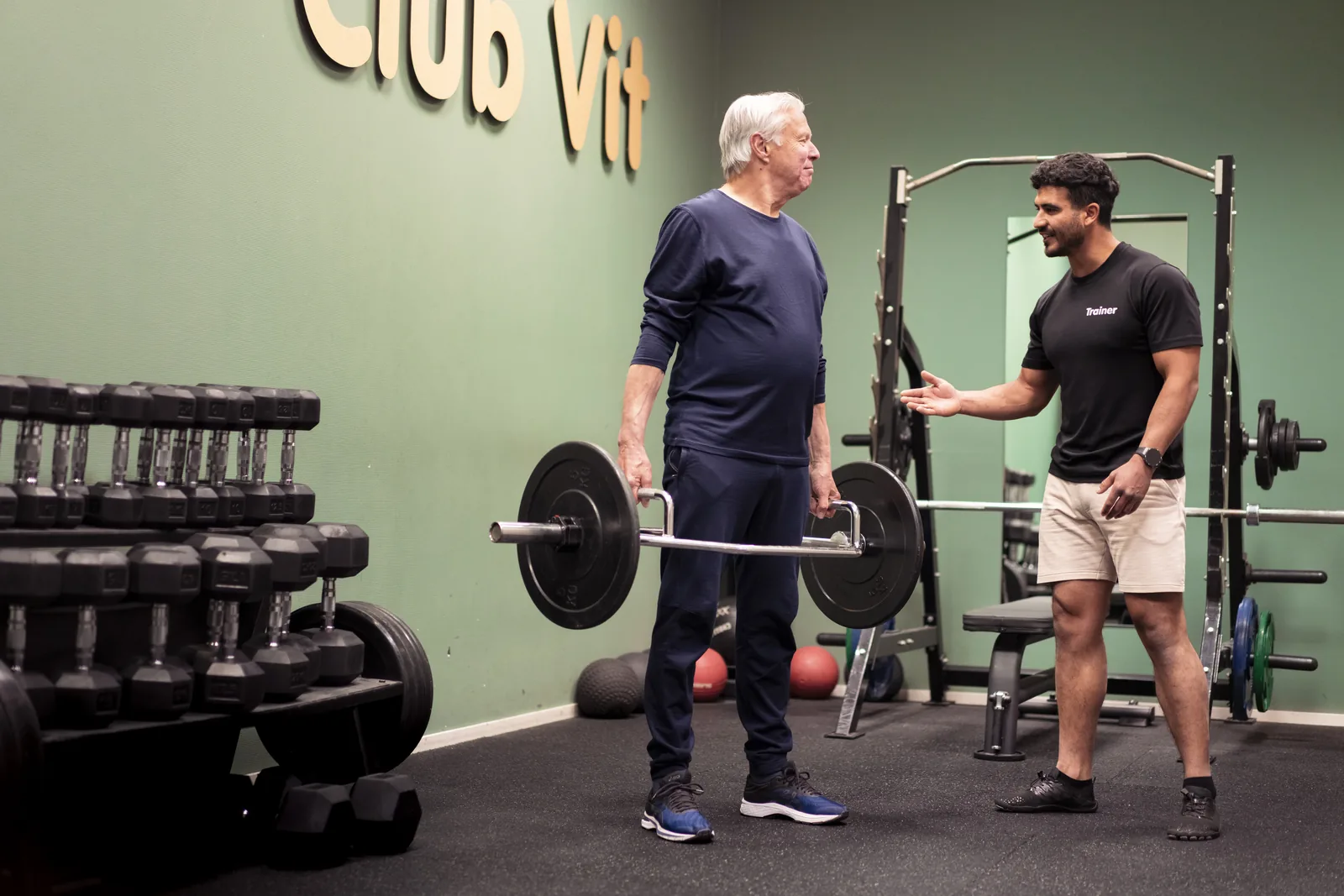 Oudere man traint met begeleiding van de trainer bij Club Vit